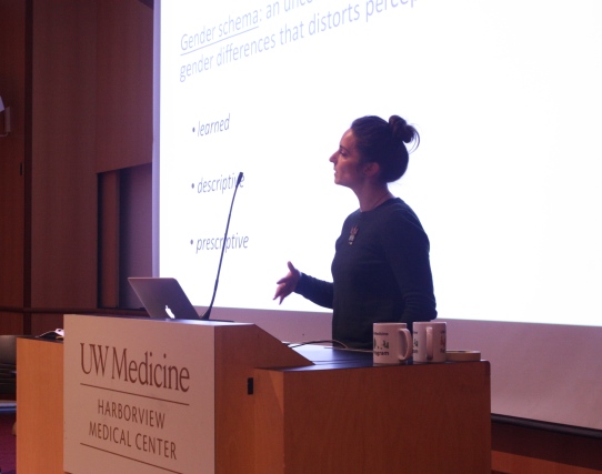 Person lecturing at a podium in front of a screen